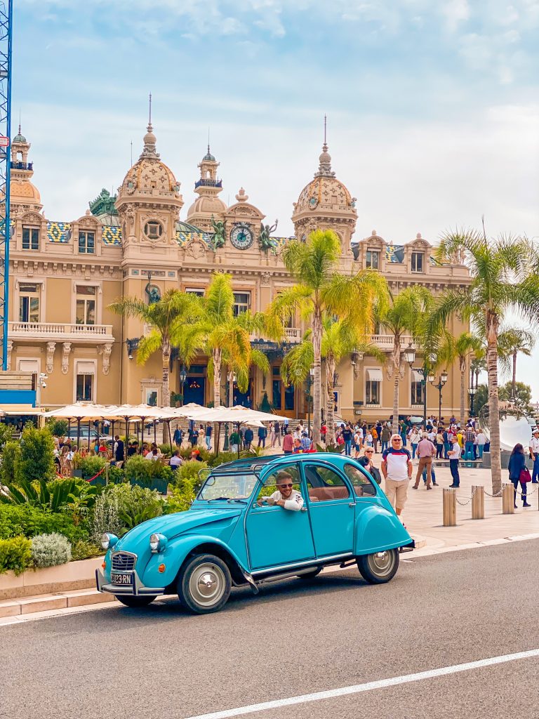 Blue 2CV Citroën car in front of Monaco Monte-Carlo Casino on the French Riviera with man driving it